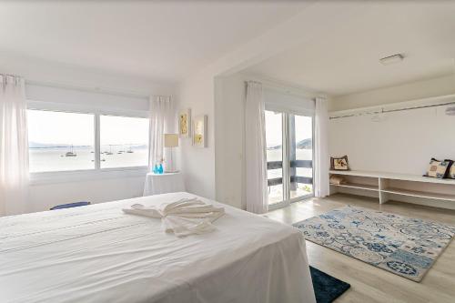 een witte slaapkamer met een bed en een groot raam bij Bela casa frente mar em Santo Antônio CDA1647 in Florianópolis