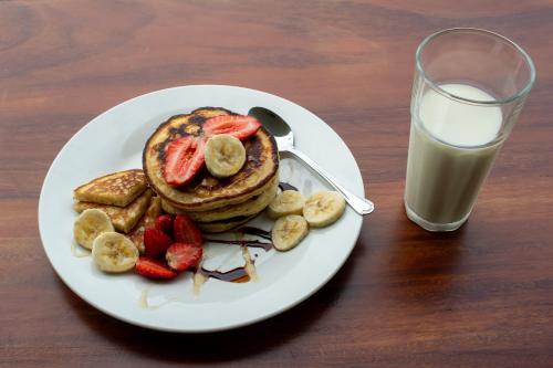a plate of pancakes and strawberries next to a glass of milk at Home La Fortuna in Fortuna