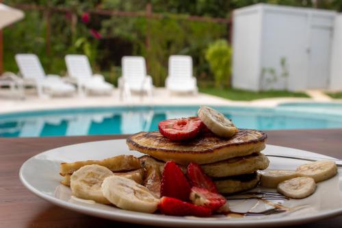 a plate of pancakes and strawberries on a table near a pool at Home La Fortuna in Fortuna