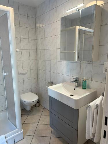 Apartment Gästehaus Tönisvorst في Tönisvorst: حمام أبيض مع حوض ومرحاض