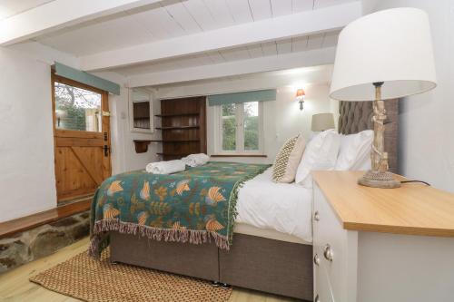 a bedroom with a bed and a table with a lamp at Myrtle Cottage in Hayle