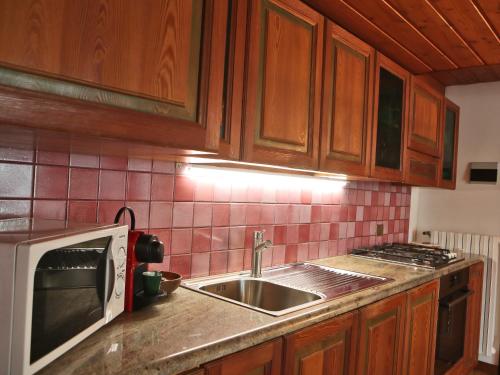 a kitchen with a sink and a microwave at Appartamento SassoMalenco in Chiesa in Valmalenco