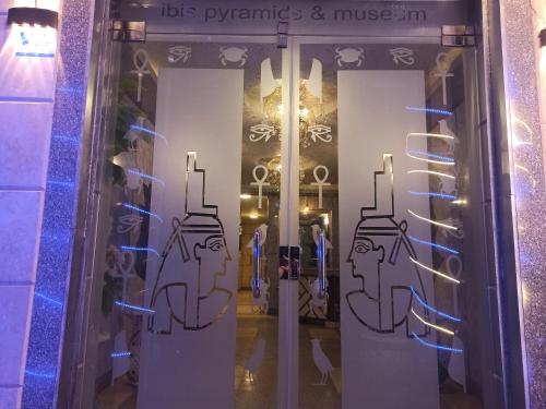 uma porta de vidro com desenhos num edifício em Ibis Pyramids&Museum view no Cairo