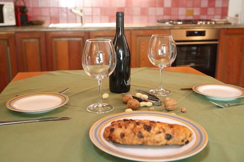 une table avec une assiette de nourriture et deux verres à vin dans l'établissement Appartamento SassoMalenco, à Chiesa in Valmalenco
