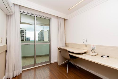 a room with a desk and a large window at GS Properties - Hotel Líder in Brasilia