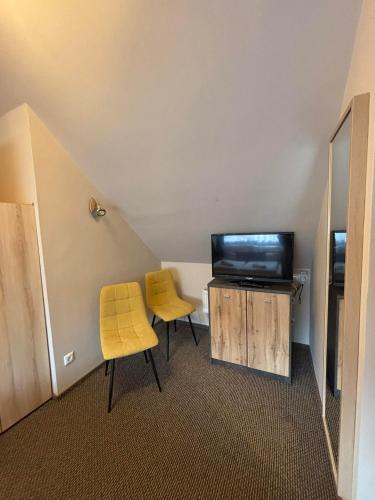 a room with two yellow chairs and a television at Centrum Vendégház in Tihany