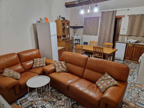 un soggiorno con divano marrone e una cucina di ESCALE AU CLOS SAINT MARTIN DE JUILLERS Gîtes et Chambres d'Hôtes a Saint-Martin-de-Juillers