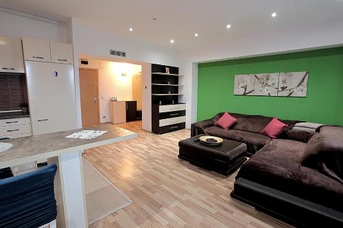 a living room with a couch and a green wall at Cataleya Suites Aparthotel in Bucharest