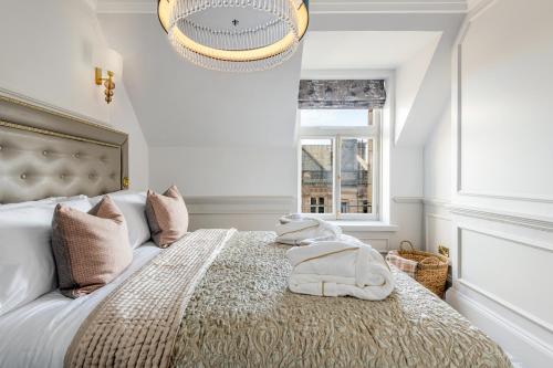 a bedroom with a large bed with a chandelier at RÌGH Residences - George Street in Edinburgh