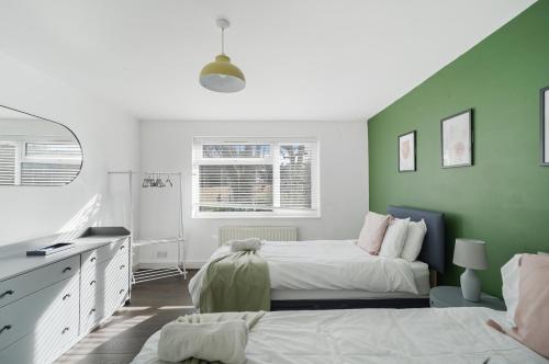 2 Betten in einem Zimmer mit grünen Wänden in der Unterkunft Stylish 3 BR House close to Streatham Hill station in London