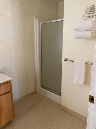 a bathroom with a glass shower door with towels at Forest Lodge Motel in Happy Camp