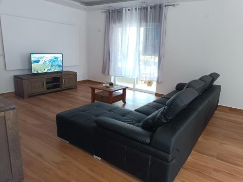 a living room with a black couch and a tv at Residência Águia in Praia