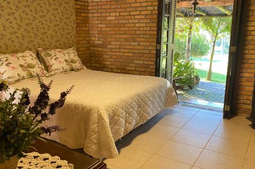 een slaapkamer met een bed en een bakstenen muur bij Casa de campo para relaxar em meio à natureza! in Treze de Maio