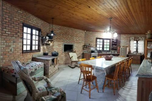 een keuken met een tafel en stoelen en een bakstenen muur bij Casa de campo para relaxar em meio à natureza! in Treze de Maio