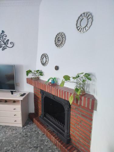 a living room with a fireplace with clocks on the wall at La casita del sillero in Jimena de la Frontera