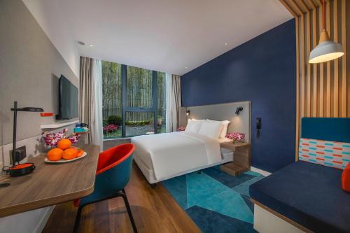 a hotel room with a bed and a table with a bowl of oranges at Holiday Inn Express Shanghai Xuhui Binjiang, an IHG Hotel in Shanghai