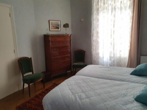 - une chambre avec un lit, deux chaises et une commode dans l'établissement Spacieux 80 m2 Cœur de Vichy proche des Thermes, à Vichy