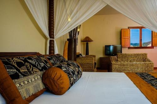 a bedroom with a bed and chairs and a television at Masía Durbá Hotel in Castellnovo