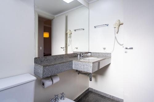 uma casa de banho com um lavatório e um WC em H4 Hotel Opera Jardins em São Paulo