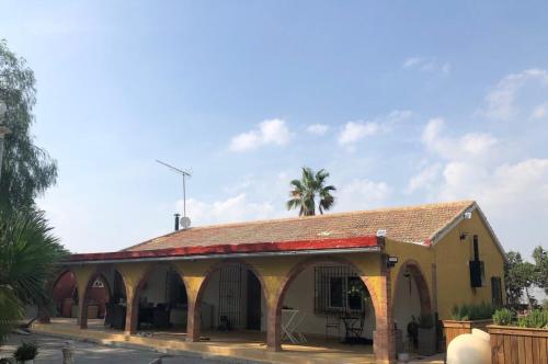 un bâtiment avec un toit rouge et un palmier dans l'établissement CASA MARIA, à Murcie