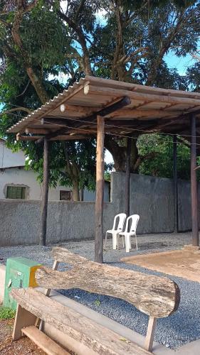 um pavilhão de madeira com cadeiras brancas e um banco em Consertamos Disco Voador em Alto Paraíso de Goiás