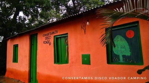 um pequeno edifício laranja com janelas verdes e graffiti em Consertamos Disco Voador em Alto Paraíso de Goiás