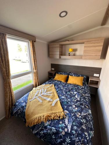 uma cama num pequeno quarto com uma janela em North Shore, Skegness, new 8 berth caravan em Lincolnshire