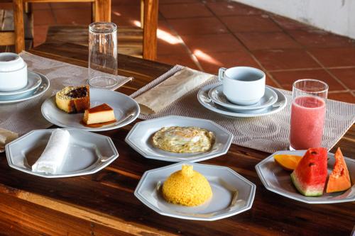 einen Holztisch mit Teller mit Speisen und Getränken in der Unterkunft Pousada Les Alizes in Icaraí