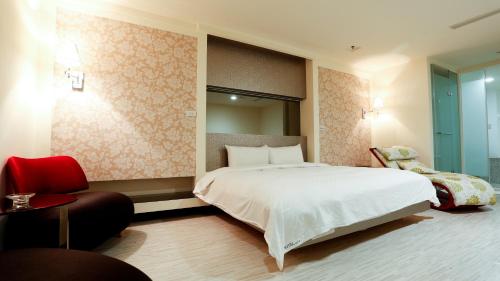 a bedroom with a large white bed and a chair at Walker Hotel - Zhengyi in Taipei