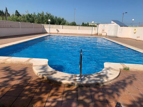 een groot zwembad met blauw water in een tuin bij Belle maison de vacances in Grao de Castellón