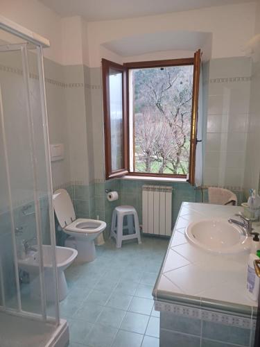 een badkamer met 2 toiletten, een wastafel en een raam bij Casa Graziella in Costacciaro