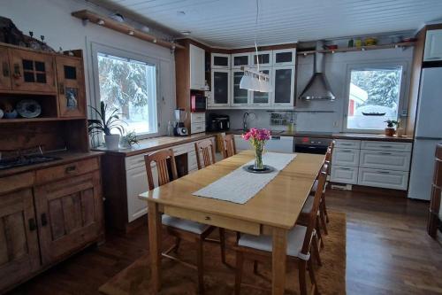 a kitchen with a wooden table with a vase of flowers on it at Coloria - kotisi Rovaniemellä, luonnollisesti in Rovaniemi