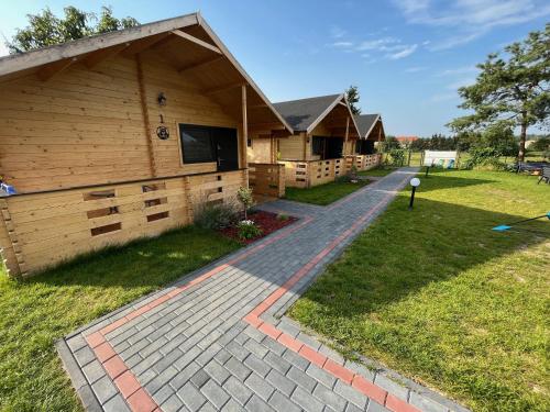 a row of wooden lodges with a walkway in the grass at Domki u Tosiek in Stegna