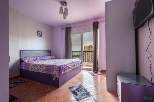a bedroom with a purple bed and a balcony at Two-Bed Room chalet in Alexandria