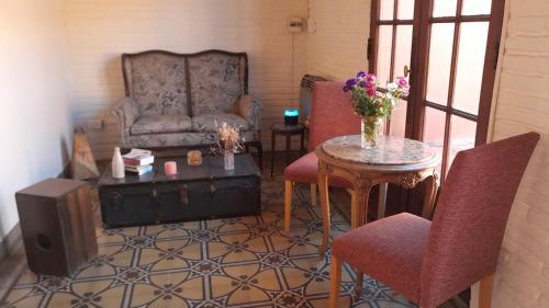 sala de estar con sofá, mesa y sillas en La Escondida, Casa de Huéspedes en San Antonio de Areco