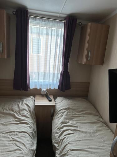 a small bedroom with a bed and a window at Sea view luxury caravan in Filey