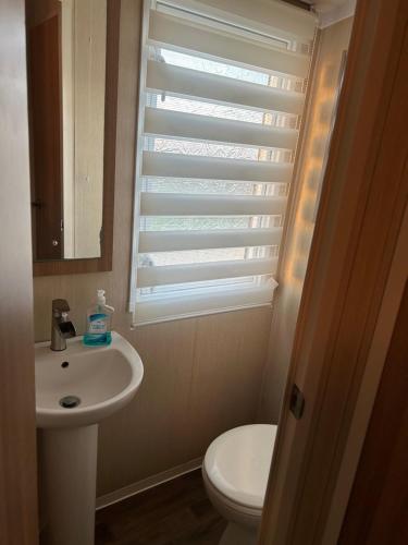 a bathroom with a toilet and a sink and a window at Sea view luxury caravan in Filey