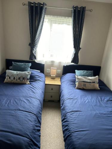 a bedroom with two blue beds and a window at 8 BIRTH LODGE ON CAYTON BAY HOLIDAY PARK in Scarborough