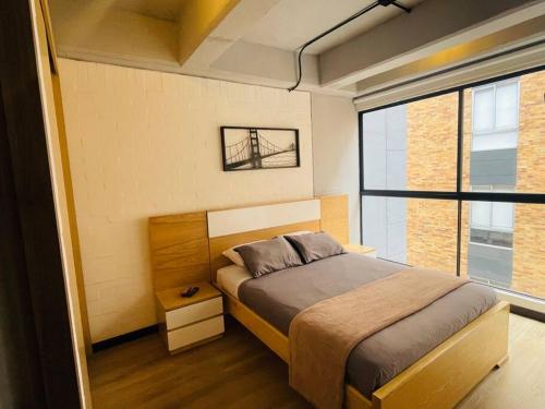 ein Schlafzimmer mit einem Bett und einem großen Fenster in der Unterkunft APTOPOR606 - Encantador apartamento tipo loft - Chapinero - Wifi - TV in Bogotá