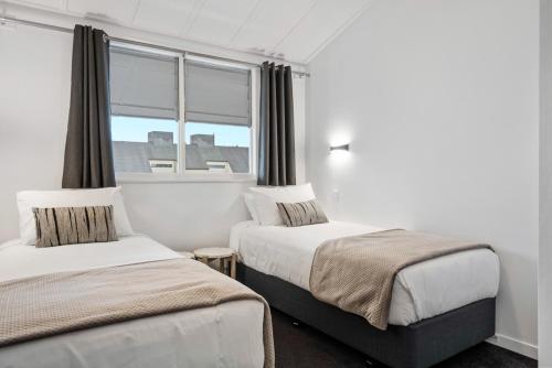 two beds in a room with a window at The Tauranga on the Waterfront in Tauranga