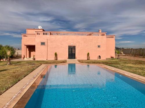 une maison avec une piscine en face d'un bâtiment dans l'établissement Family villa with swimming pool and a wonderful mountain view, à Marrakech