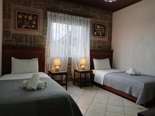 a bedroom with two beds and a window and two lamps at Elaias Gea -Kalampaka in Kalabaka