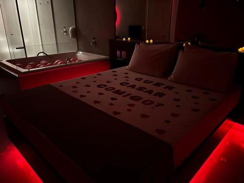 a bedroom with a bed and a bathtub with red lights at Oasis Motel in Piracicaba
