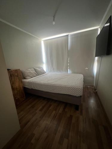 una piccola camera da letto con un letto illuminato di HABITACIÓN GRANDE CON BAÑO en departamento compartido a Santiago