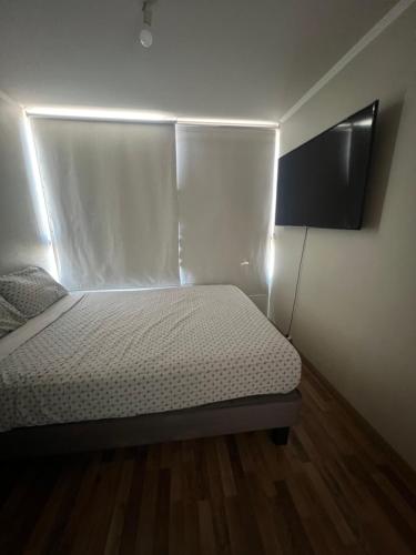 Habitación pequeña con cama y TV de pantalla plana. en HABITACIÓN GRANDE CON BAÑO en departamento compartido en Santiago