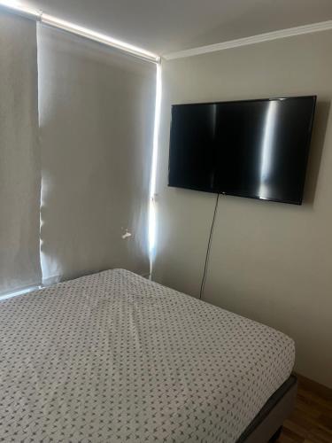a bedroom with a bed with a television on the wall at HABITACIÓN GRANDE CON BAÑO en departamento compartido in Santiago