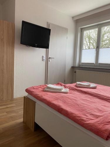 a bedroom with a red bed with a flat screen tv on the wall at Pension Feist Zimmer4 in Dagebüll