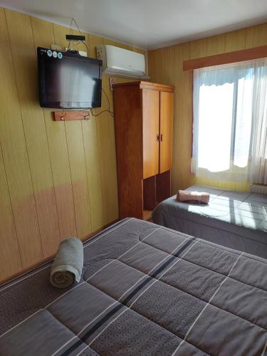 a bedroom with a bed and a tv on the wall at Hostal Prat 2 in Valdivia