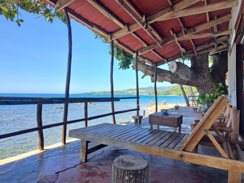 a wooden porch with a bench on the beach at Paseo Del Mar Seaside Inn in Jagna