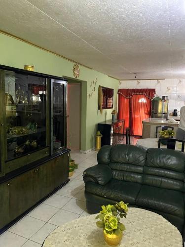 ein Wohnzimmer mit einem Ledersofa und einem Tisch in der Unterkunft Casa Fransina in Blue Bay